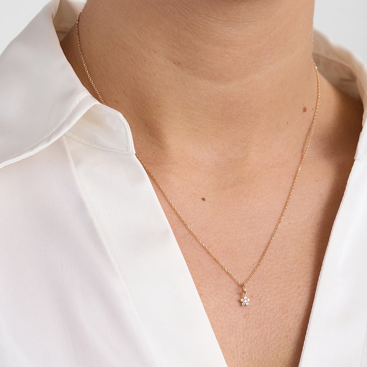 Guld halskæde med lille blomsterformet vedhæng og diamanter, forside på model