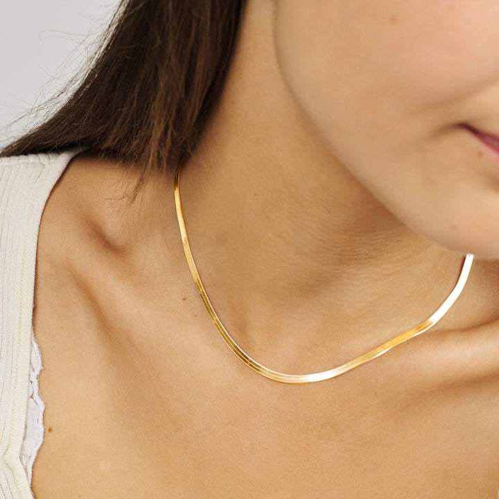 Herringbone Necklace 18kt Gold Plated ses på halsen af en kvinde, elegant og blank overflade. Model 7220319