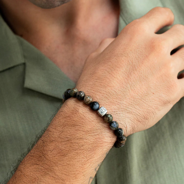 Alexander Lynggaard Armbånd Glaucophane 8mm vises på en mands hånd, perler i blåbrune nuancer. Model C01180-001.