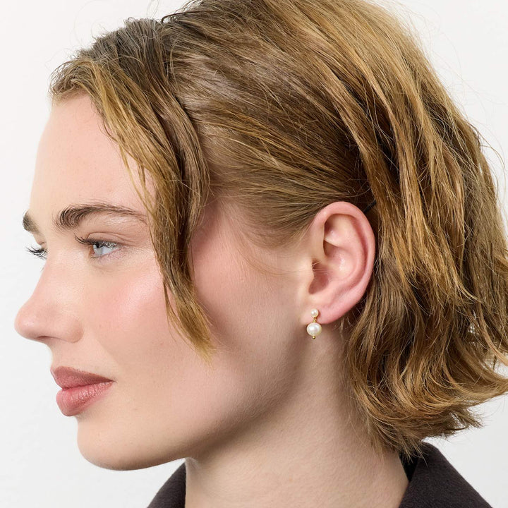 carre-sally-forgyldte-orestikker-m-ferskvandsperler vist på model, cremefarvet perle og gulddetalje. Model FS4582BI-BI-2