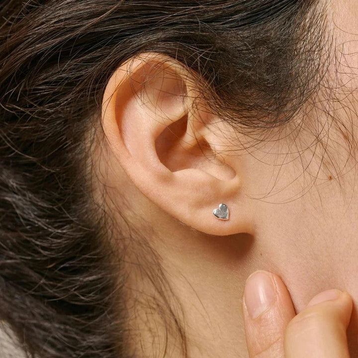 Enamel Heart Studs vises som sølvfarvet hjerteørering i øre på model, elegant og minimalistisk. Model E373SM-E373SM-2