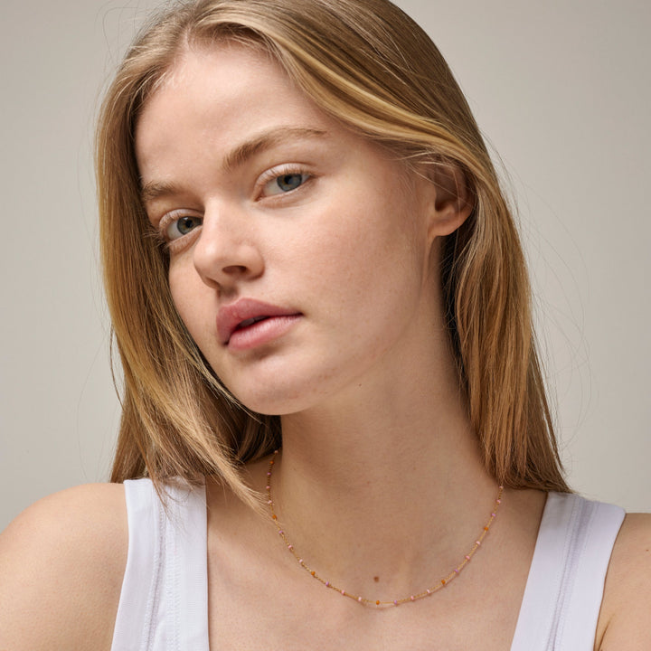 Enamel Lola halskæde blush i forgyldt sølv vises på model, delikate rosa nuancer skinner let. Model N55G-BLUSH-2