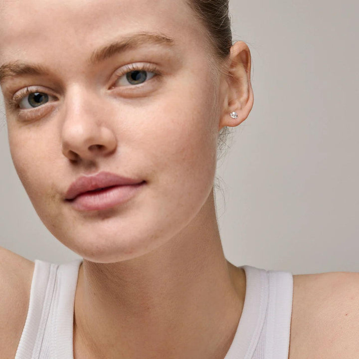 Enamel Organic Clover Små Firkløver Ørestikker i sølv ses på øret af model, diskret design Model e412sm