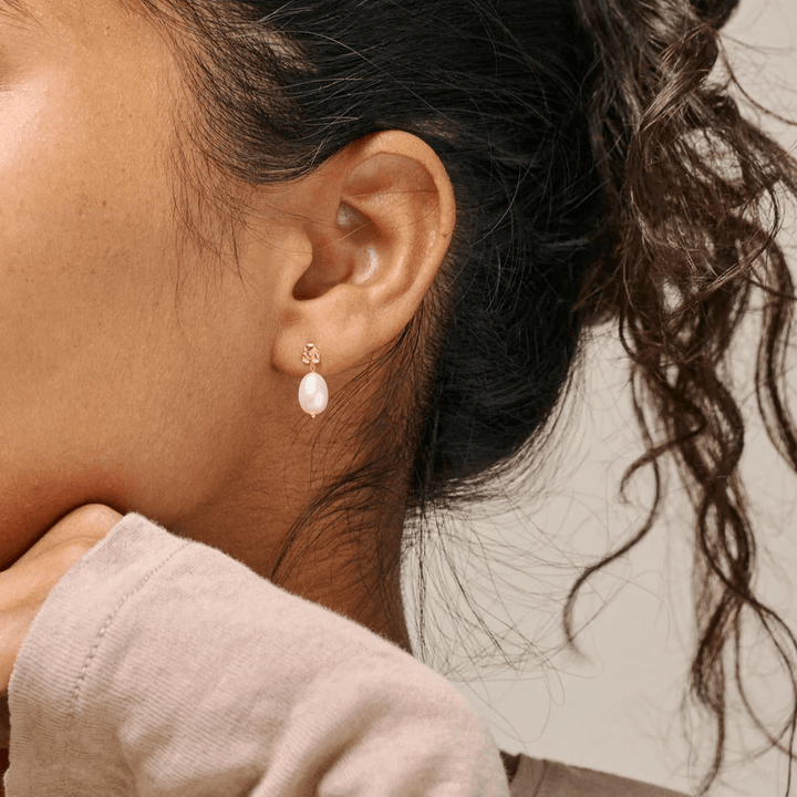 Enamel Poe Pearl Studs vises her båret på øre, elegant ferskvandsperle og guldtonet detalje. Model e384gm-pearl