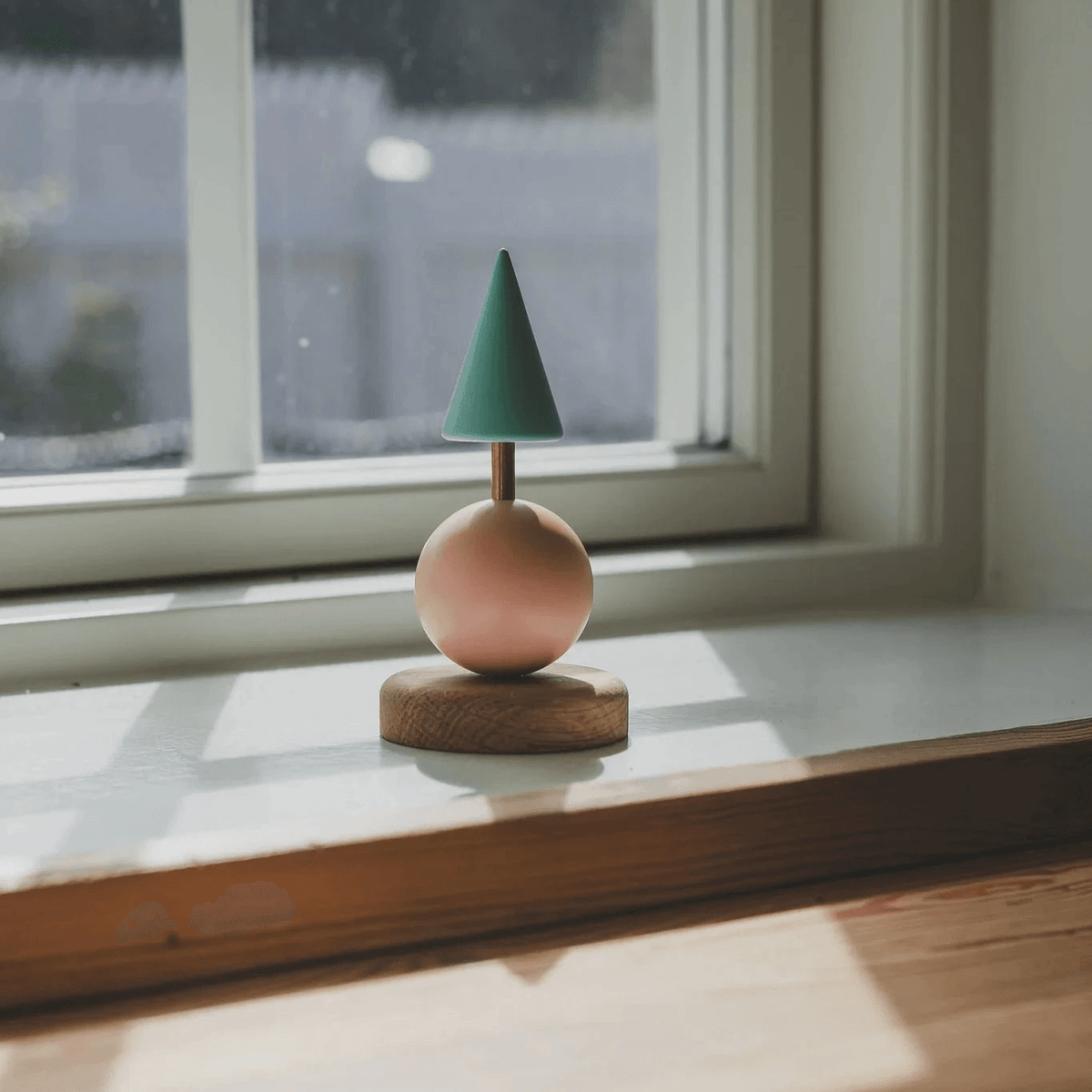Fablewood Juletræ Astrid står på en vindueskarm, med grøn top og rosa kugle på træfod. Model1210-1