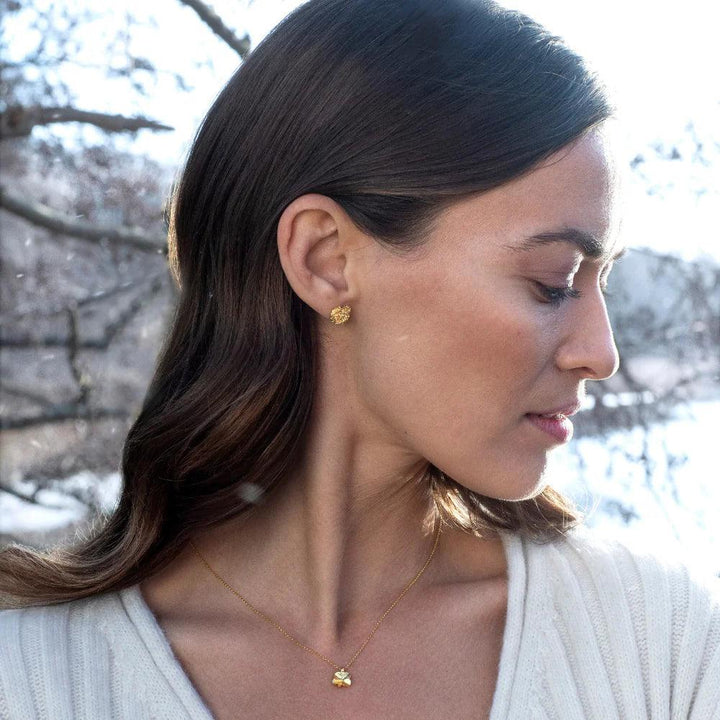 Flora Danica Firklover halskæde 18kt guld vises båret af kvinde i natur med Model flc-ne-18k-g-2.