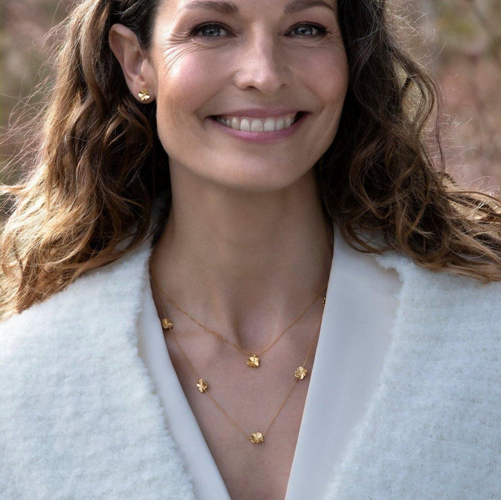 Flora Danica Firklover halskæde med fem kløver, bæres af kvinde, guldlook udendørs. Model flc-nelo-g-2