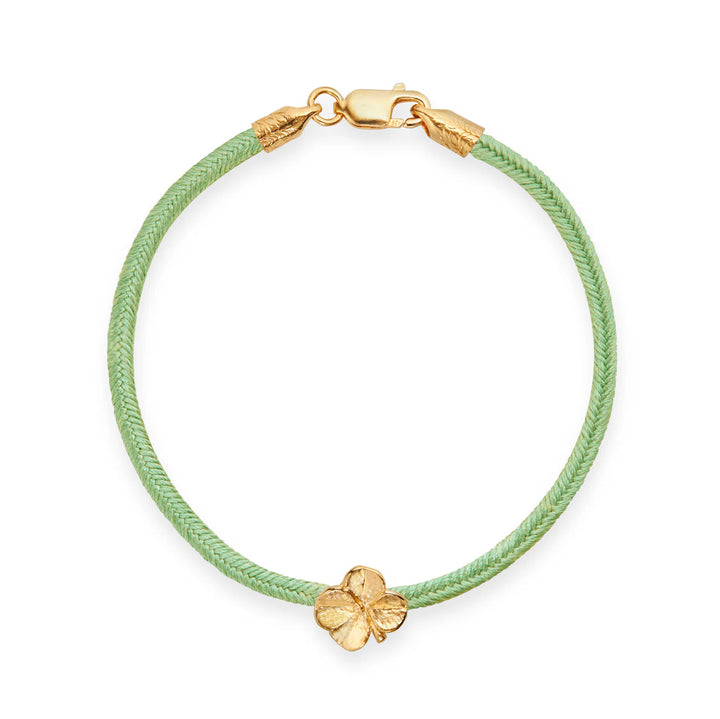 Flora Danica Firklover Silke Armbånd Lysegrøn Forgyldt viser et elegant lysegrønt armbånd i silke med forgyldt kløverdetalje og lukning. Model 907-flc-silk-lightgreen-g-001-1