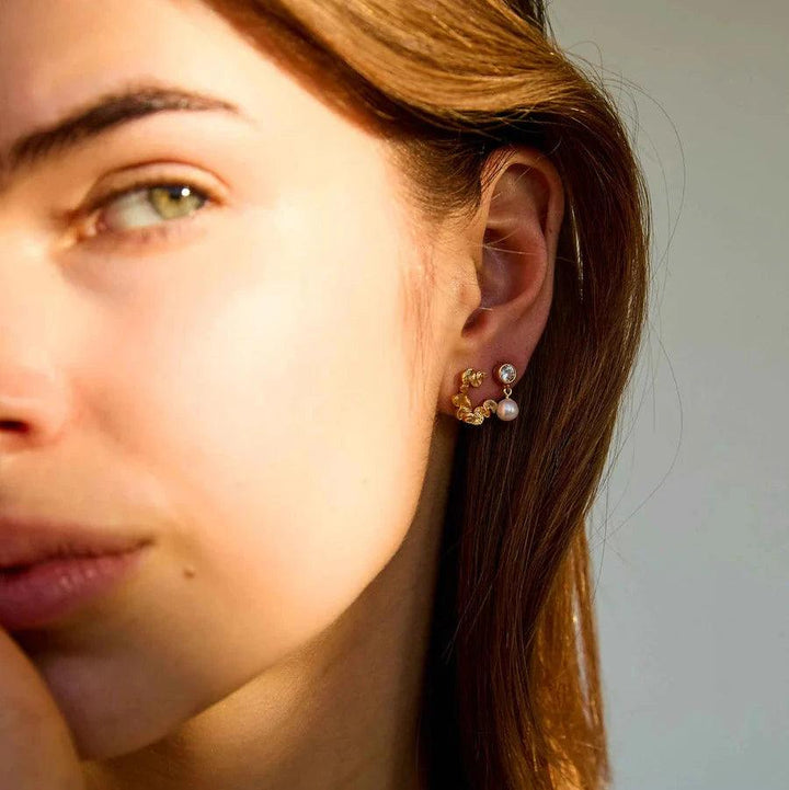 Hultquist Copenhagen Audrey Petite forgyldte øreringe med perle og sten ses på øre, Model S08603G-2.