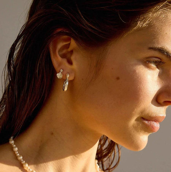 Hultquist Copenhagen Lainey Petite sølv ørestikker vises på model med perlekæde i sollys. Model S08610S-2