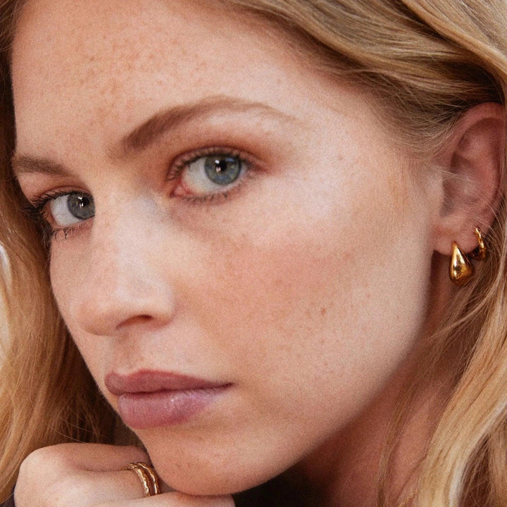 Jeberg Jewellry Audrey Drop Øreringe i guldtonet metal på kvinde med lyst hår, Model52920-1