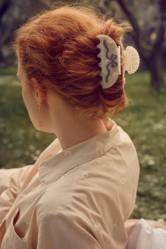 maanesten-desiree-hair-claw-off-white ses i kvindens opsatte røde hår, i solrigt udendørsmiljø. Model 3973-onesize