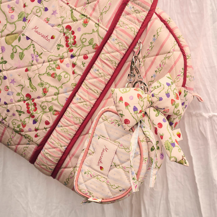 Maanesten Fabric Bow Nøglering Garden Magic Ivory vises på en quiltet taske, blomstret og pastelfarvet. Model 4111-onesize