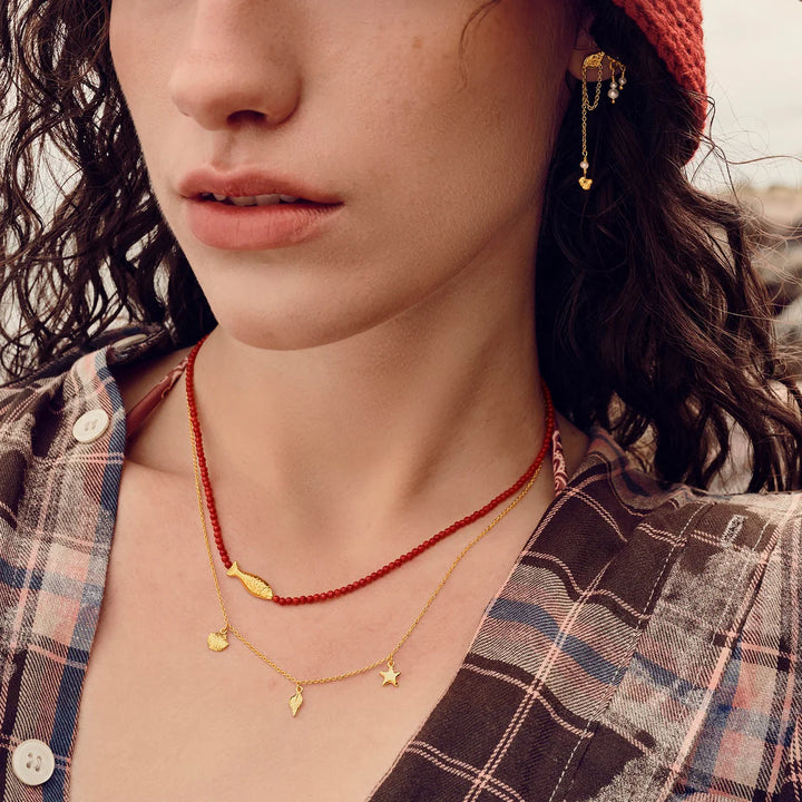 maanesten-iluka-halskaede-forgyldt med gyldne charms og røde perler, båret af kvinde, Model 2818a-2