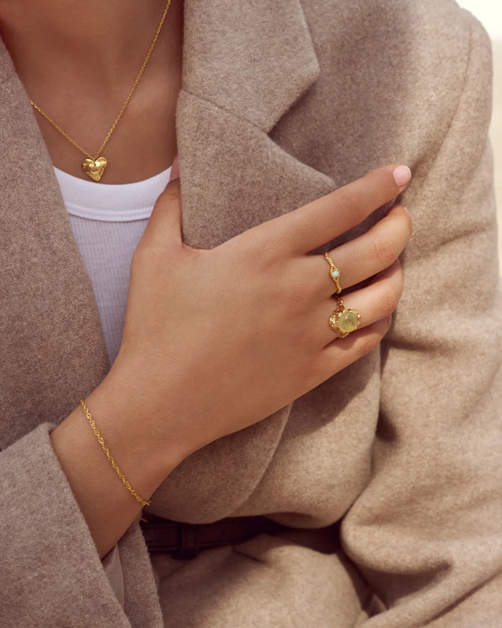 Maanesten Lisa forgyldt ring vises på en hånd med beige frakke, guldfarvet, unik struktur. Model 4745a-001-2.