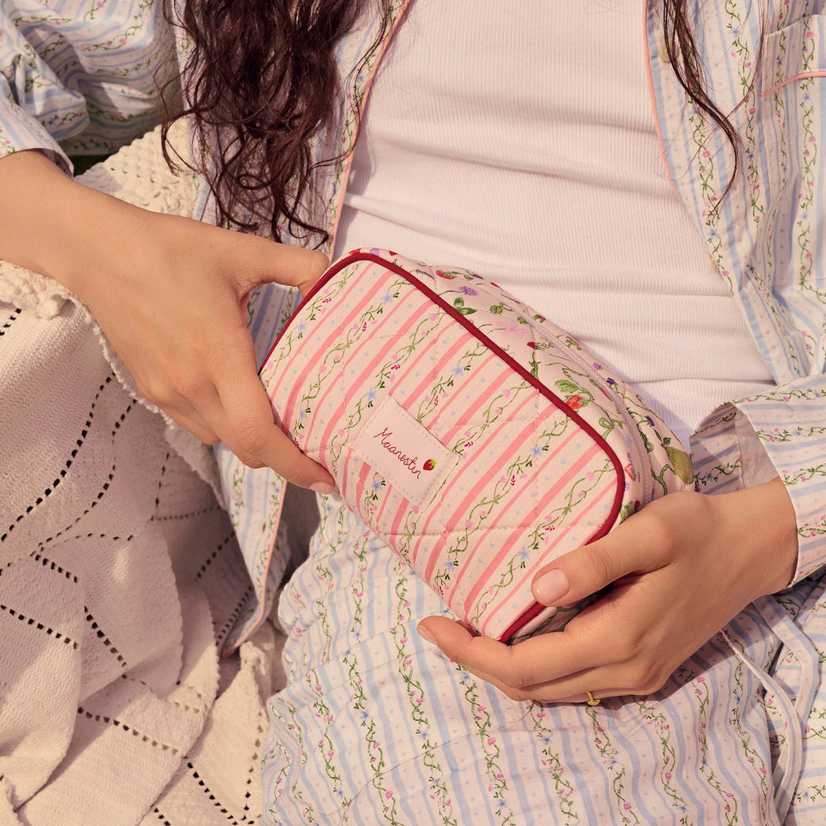 maanesten-stardust-bag-summer-stripes-peach med lyserøde og grønstribede blomstermønstre holdes i skødet. Model4114-onesize