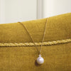 Mads Z Celeste 14kt guld vedhæng med kulturperle og diamant på kæde, vist på gul velouroverflade. Model 1533133-2
