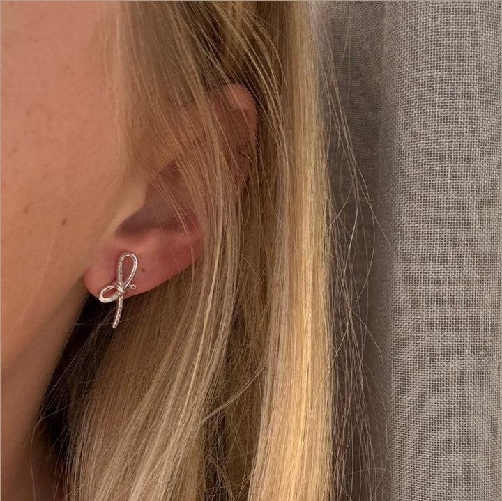 Mads Z Miss Butterfly sløjfe ørestikker i sølv med hvid topas vises på øre. Model 2116003-2