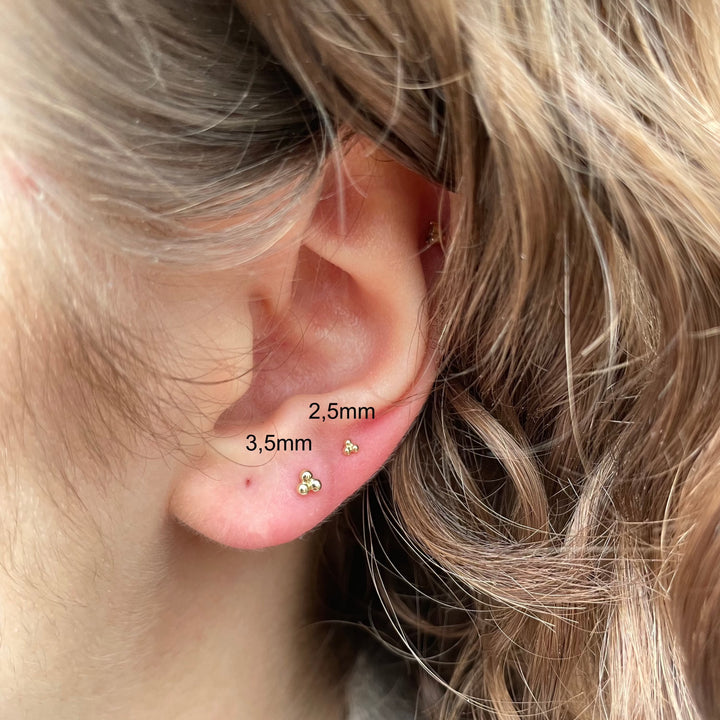 Maria Tash Large Three Ball Trinity Threaded Stud i guld båret i øre, minimalistisk stil. Model 35mm-x3btrl-001.