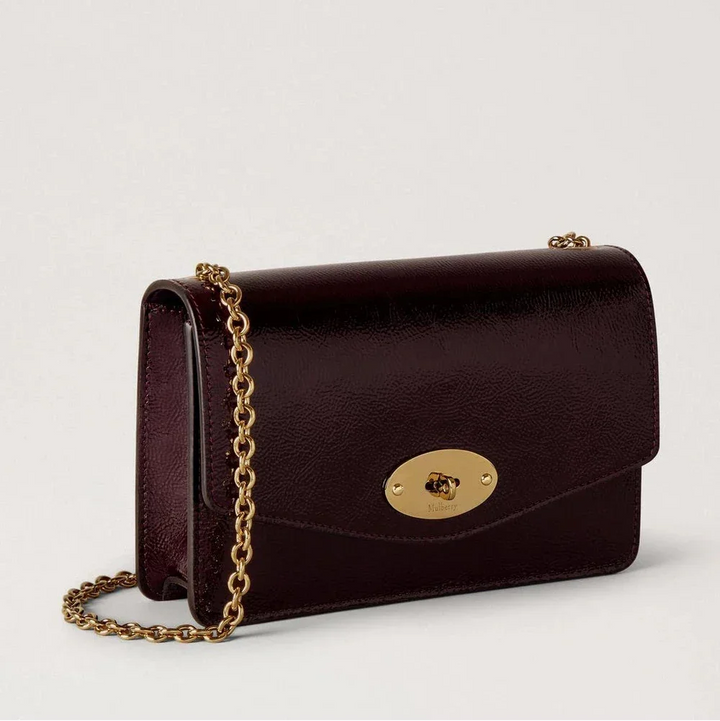 Mulberry Small Darley Deep Aubergine Patent viser en lille, glansfuld skuldertaske i mørk auberginefarvet læder med gylden kæderem. Model RL8922737V697