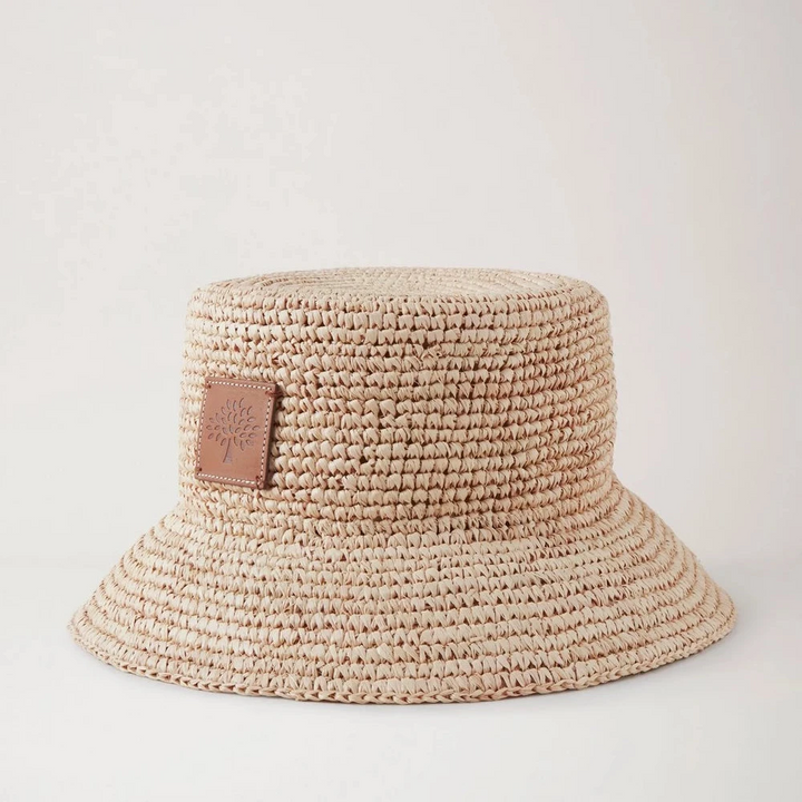 Mulberry Summer Raffia Bucket Hat viser en lys, flettet sommerhat i raffia med læderpatch. Model VH4097807H120.