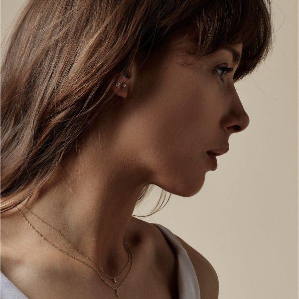 Nuran 14kt Zoe orestikker vises diskret på øret af kvinde, enkel og elegant i guld. Model o2314-006rg-2.