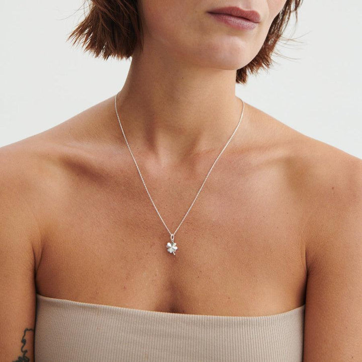 Pernille Corydon Clover Pendant, et forgyldt firkløver vedhæng bæres om halsen på model. Model P-964-GP-2
