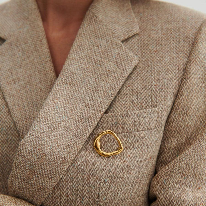 Pernille Corydon Gaia Forgyldt Sølv Broche ses på en beige jakke, organisk gylden form, Model C-001-GP