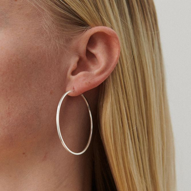 Pernille Corydon Orbit Store Hoops i sølv vises båret i øret på model med lyst hår. Model E-053-S