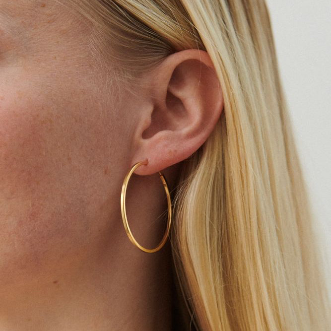 Pernille Corydon Small Orbit Hoops forgyldt båret på øre, slank rund gylden ørering. Model E-052-GP.
