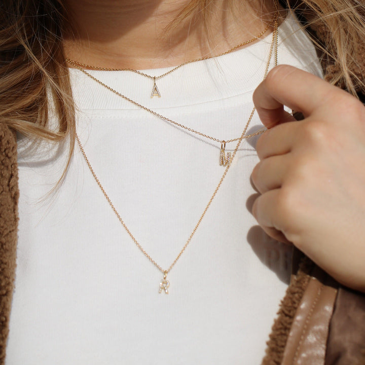 ro copenhagen my collection med diamanter, guldhalskæder med bogstavvedhæng båret på hvid bluse, Model p114y2-001-2