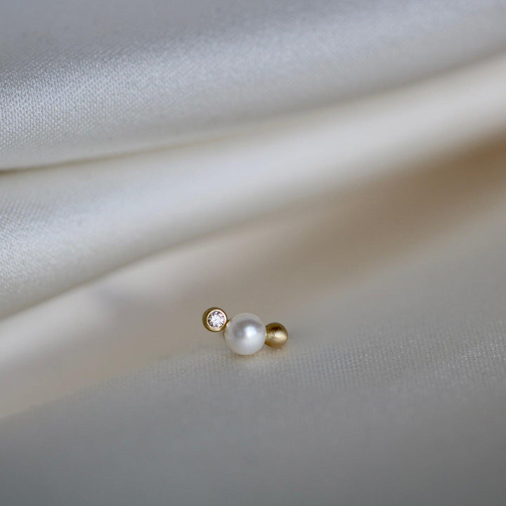 RO Copenhagen Orbit Dot WWF Ørestikker viser en enkelt perle, diamant og gulddetalje på lyst stof. Model E118Y103-2