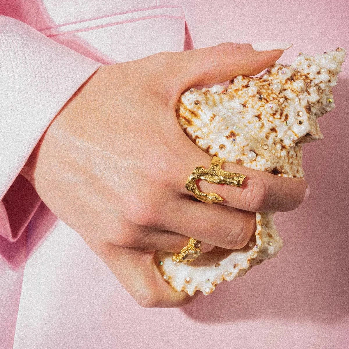 Vincent Bone Forgyldt Ring vist på hånd, detalje af guldfarvet ring mod en konkylie. Model vj229-urg-001