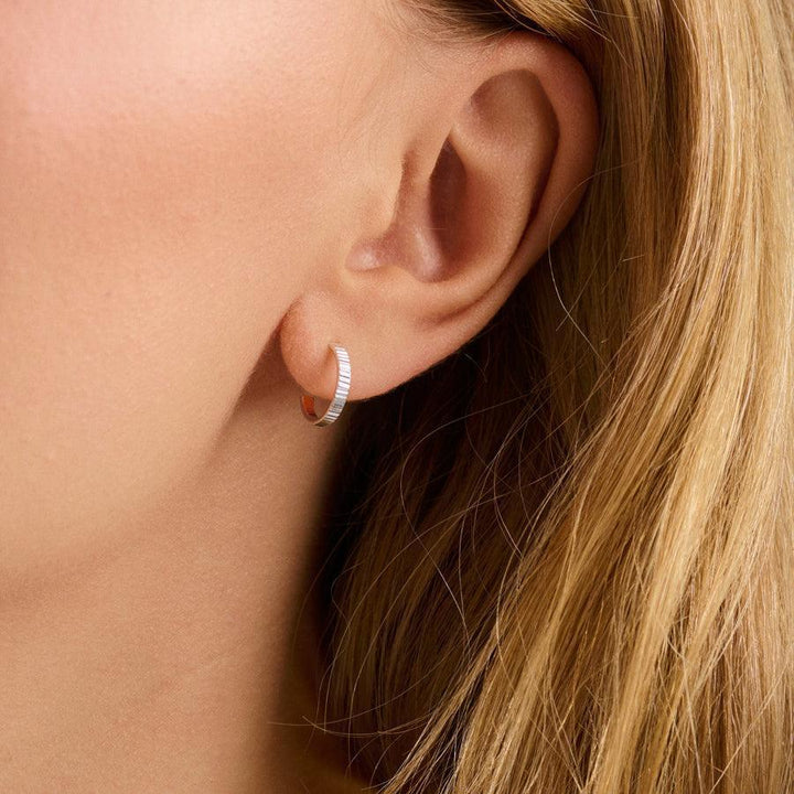 Pernille Corydon Sea Reflection Mini Hoops vist i øret, sølvfarvet creol med riflet overflade. Model E-483-S