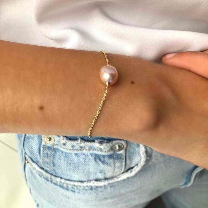 ro copenhagen 18kt fryd armband med rosa barok vises om håndled, elegant guldarmbånd med perle. Model 192l0013-002